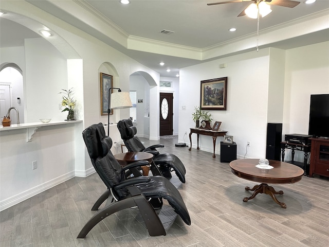 living room with light wood-type flooring, crown molding, sink, and ceiling fan