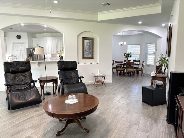 interior space featuring a tray ceiling, an inviting chandelier, light hardwood / wood-style floors, and ornamental molding