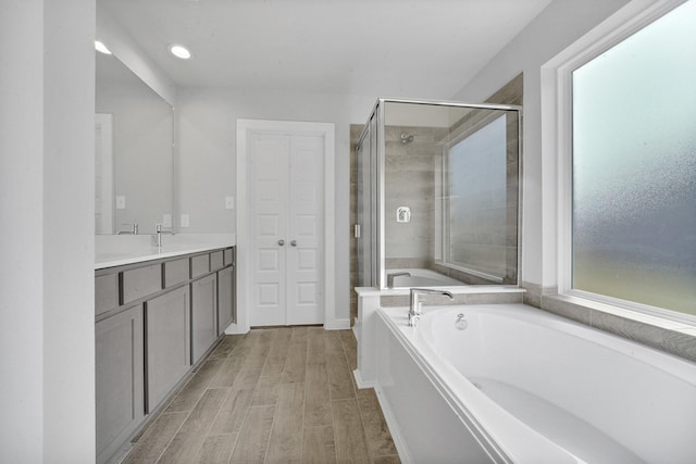 bathroom featuring vanity, wood-type flooring, and shower with separate bathtub