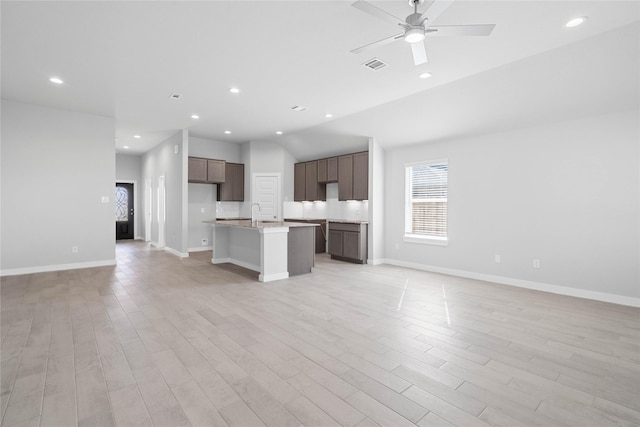 kitchen featuring open floor plan, light wood-style flooring, visible vents, and a kitchen island with sink