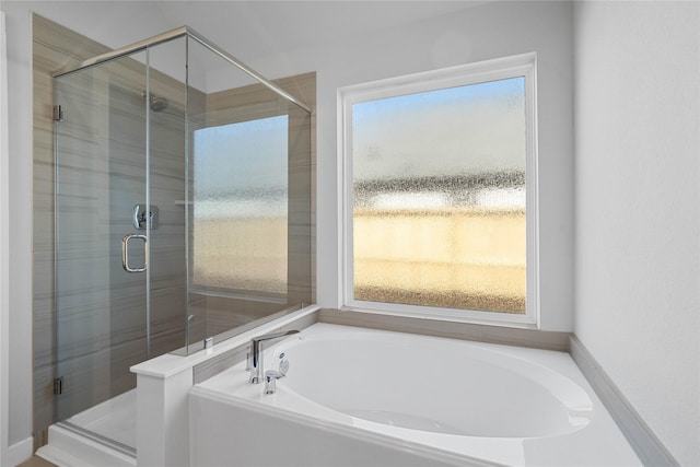 full bath with plenty of natural light, a garden tub, and a shower stall