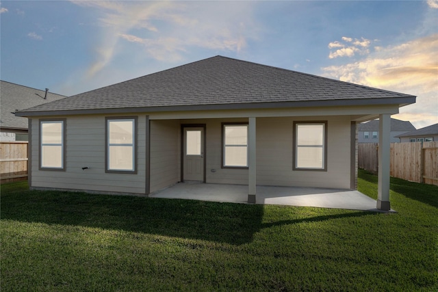 back of house with a yard, a patio, roof with shingles, and fence