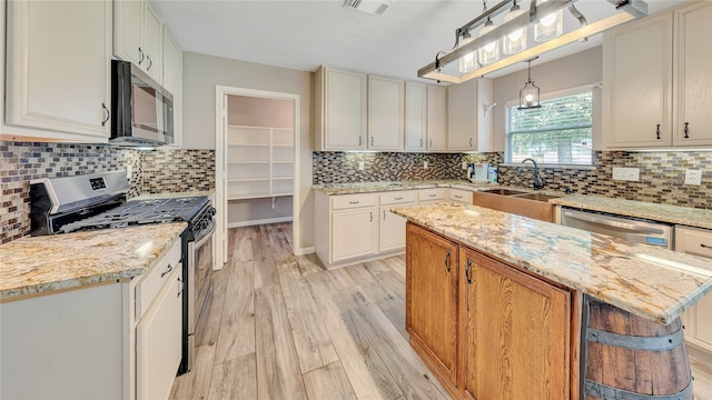 kitchen with appliances with stainless steel finishes, tasteful backsplash, a center island, and sink