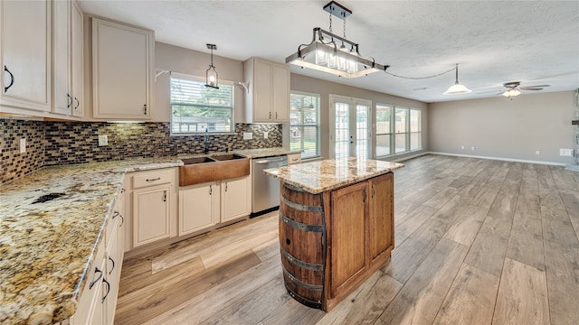 kitchen featuring dishwasher, light hardwood / wood-style flooring, light stone counters, ceiling fan, and a kitchen island