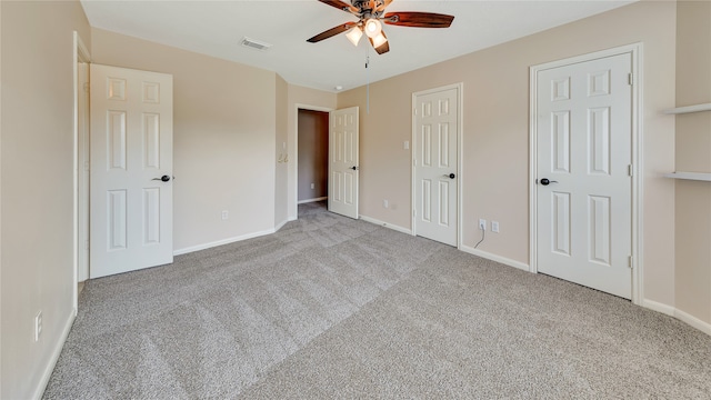 unfurnished bedroom featuring multiple closets, ceiling fan, and light colored carpet