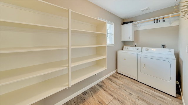 laundry room with light wood-type flooring, cabinets, and washing machine and clothes dryer