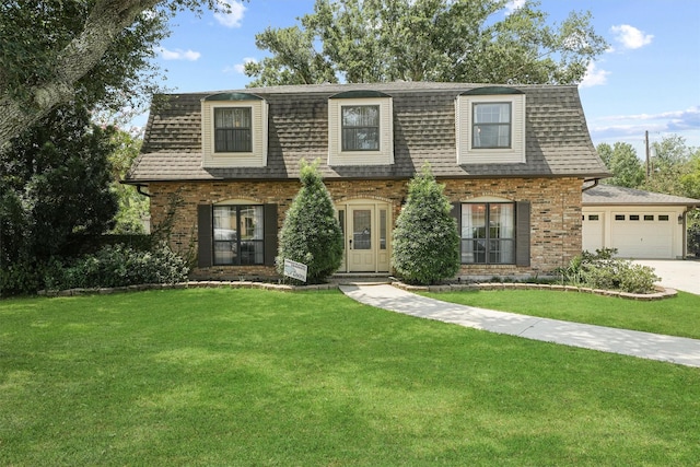 view of front of home with a shingled roof, a front yard, concrete driveway, and brick siding