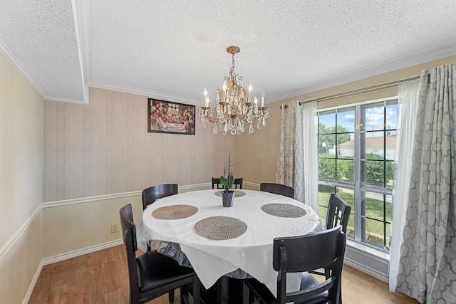 dining room with crown molding, a textured ceiling, hardwood / wood-style flooring, and an inviting chandelier