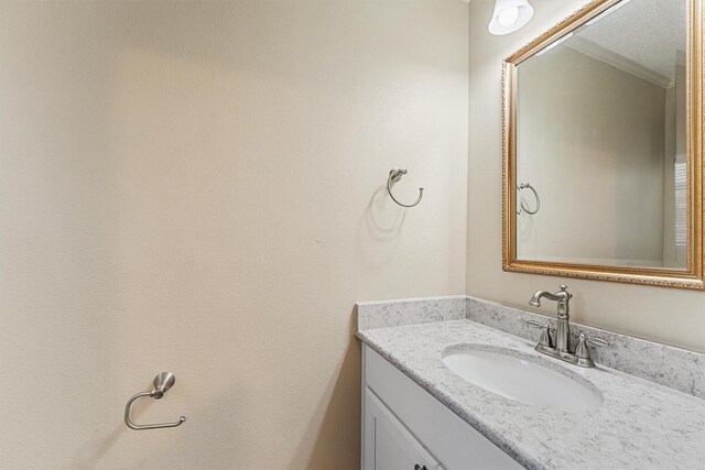 bathroom with a textured ceiling, vanity, and crown molding