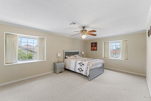 carpeted bedroom featuring a textured ceiling, a ceiling fan, baseboards, visible vents, and crown molding