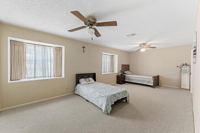 carpeted bedroom with visible vents, ceiling fan, a textured ceiling, and baseboards