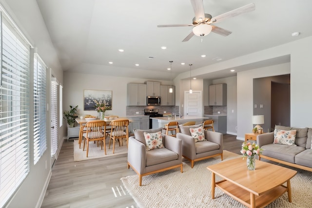 living room with ceiling fan and light hardwood / wood-style flooring