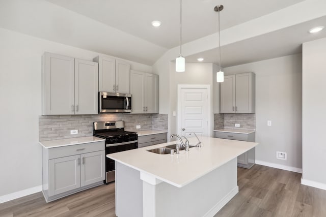 kitchen with sink, decorative light fixtures, appliances with stainless steel finishes, gray cabinets, and an island with sink