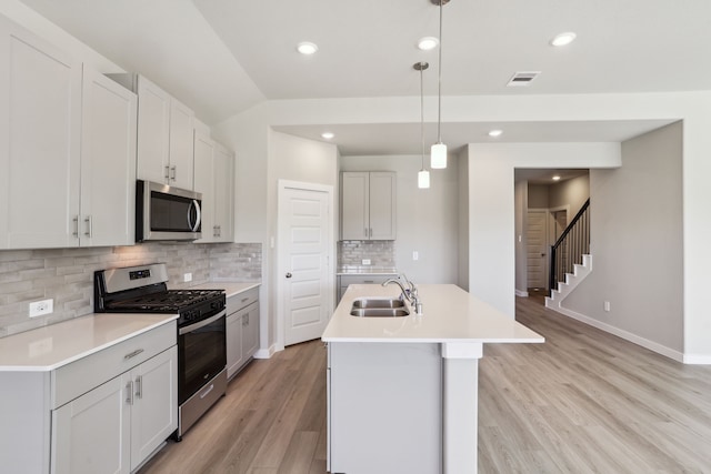 kitchen with pendant lighting, sink, appliances with stainless steel finishes, an island with sink, and white cabinets