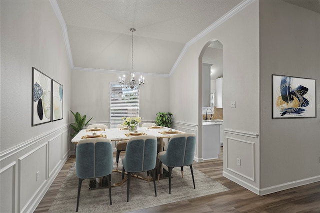 dining area with crown molding, a textured ceiling, a chandelier, dark wood-type flooring, and lofted ceiling