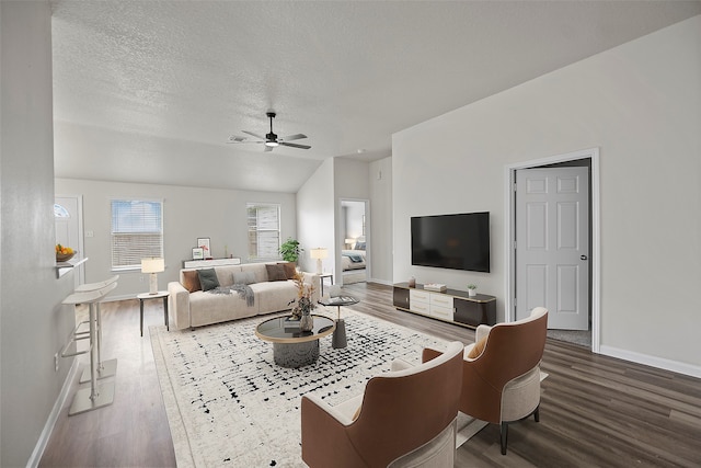 living room featuring dark wood-type flooring, ceiling fan, and a textured ceiling