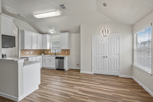 kitchen with white cabinets, light hardwood / wood-style floors, lofted ceiling, tasteful backsplash, and stainless steel dishwasher