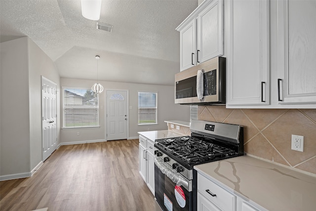 kitchen featuring white cabinets, backsplash, light wood-type flooring, appliances with stainless steel finishes, and a textured ceiling