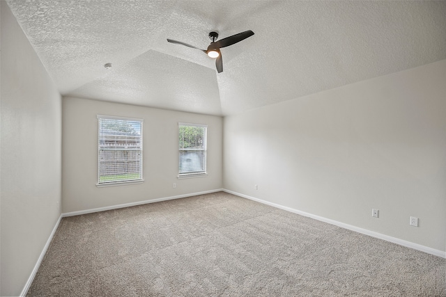 carpeted spare room featuring ceiling fan, vaulted ceiling, and a textured ceiling