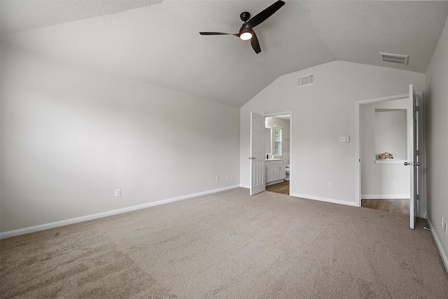 unfurnished bedroom with lofted ceiling, light colored carpet, ceiling fan, and connected bathroom