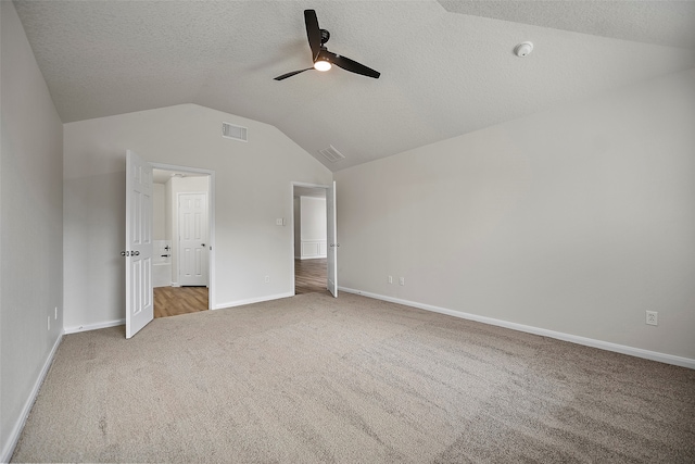 unfurnished bedroom with light carpet, vaulted ceiling, a textured ceiling, and ceiling fan