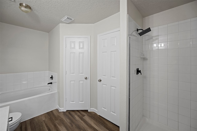 bathroom with a textured ceiling, toilet, wood-type flooring, and shower with separate bathtub