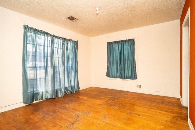 spare room with a textured ceiling and wood-type flooring