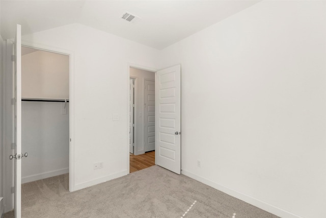 unfurnished bedroom with light carpet, a closet, and lofted ceiling