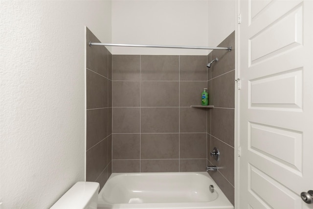 bathroom with toilet and tiled shower / bath