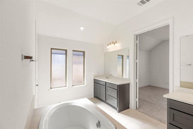 bathroom featuring tile patterned floors, vanity, lofted ceiling, and a tub