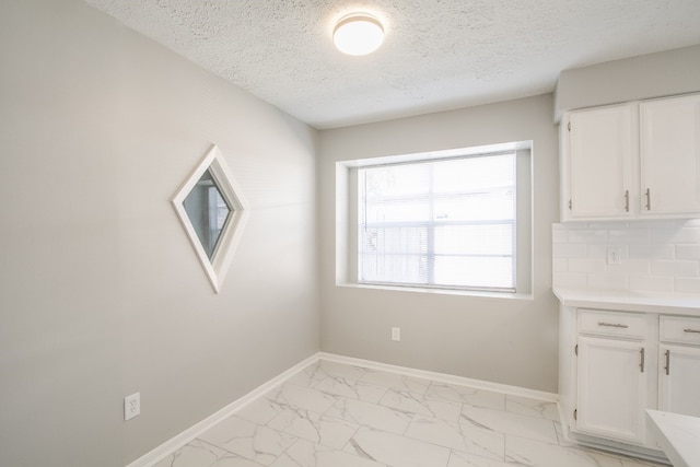 unfurnished dining area with a textured ceiling and light tile patterned floors