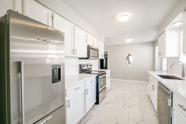 kitchen with white cabinetry, tasteful backsplash, light tile patterned floors, stainless steel appliances, and sink