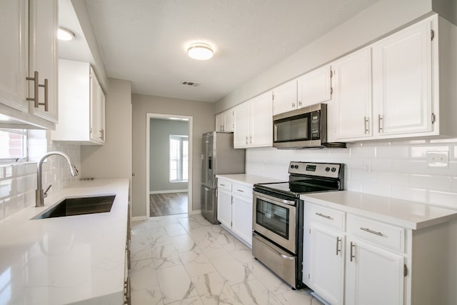 kitchen featuring light wood-type flooring, white cabinets, a wealth of natural light, and stainless steel appliances