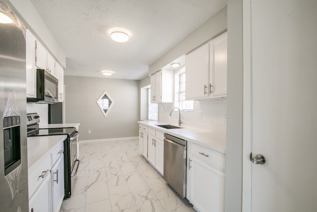 kitchen with light tile patterned floors, appliances with stainless steel finishes, white cabinetry, sink, and tasteful backsplash