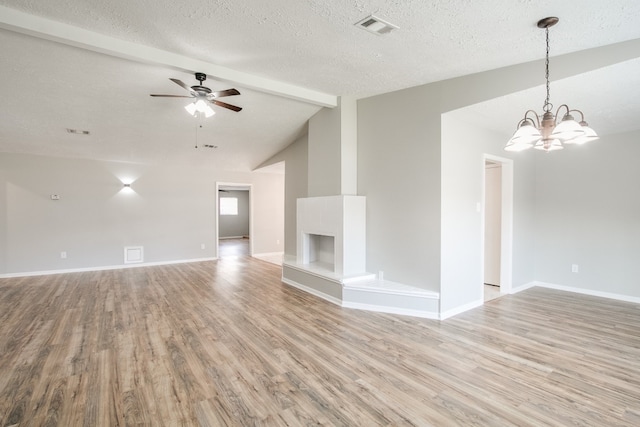 unfurnished living room with light hardwood / wood-style flooring, ceiling fan with notable chandelier, a textured ceiling, and vaulted ceiling