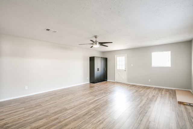 empty room with light wood-type flooring, a textured ceiling, and ceiling fan