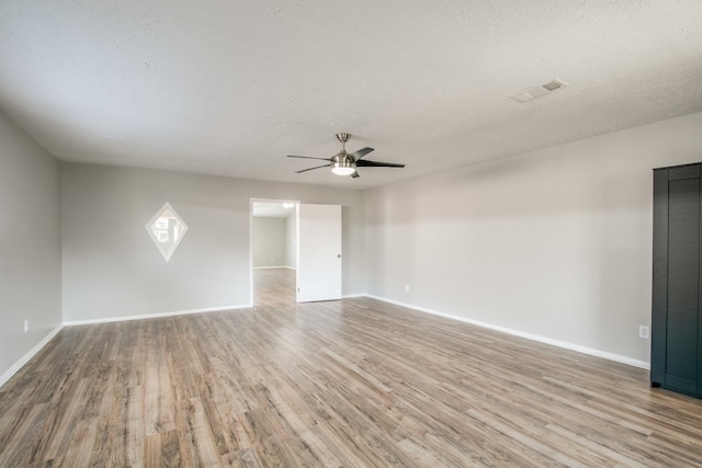 empty room with a textured ceiling, ceiling fan, and wood-type flooring