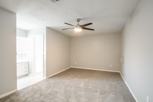 carpeted empty room featuring ceiling fan and a textured ceiling