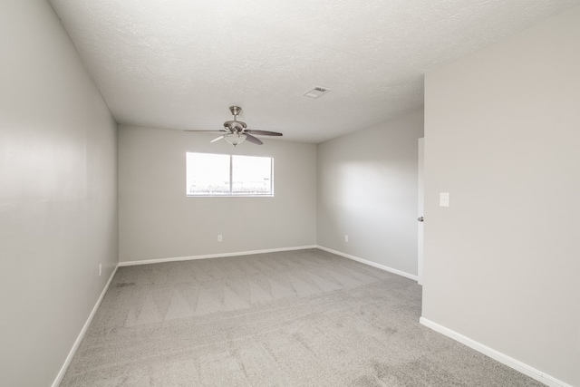 spare room with light colored carpet, a textured ceiling, and ceiling fan