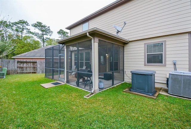 back of property with a lawn, a sunroom, and central AC