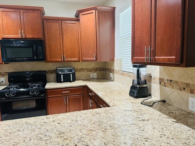 kitchen with black appliances, backsplash, and light stone countertops