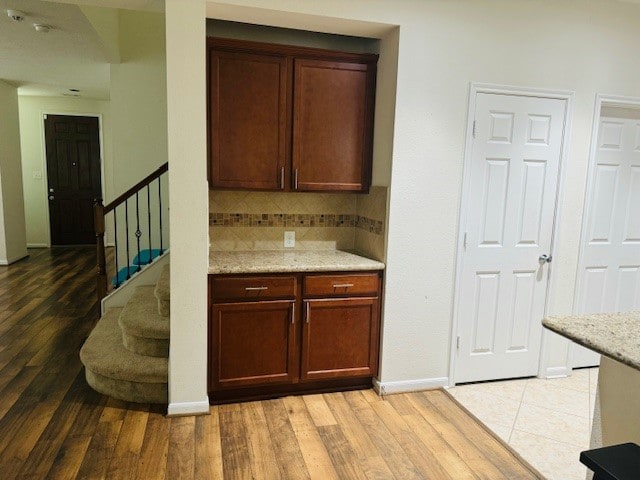 kitchen with tasteful backsplash, hardwood / wood-style floors, and light stone countertops