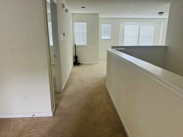 hall featuring a textured ceiling and light colored carpet