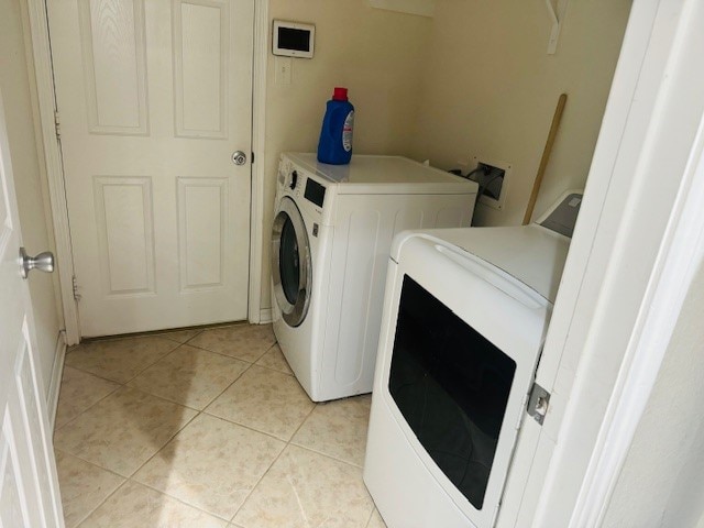 laundry area with independent washer and dryer and light tile patterned flooring