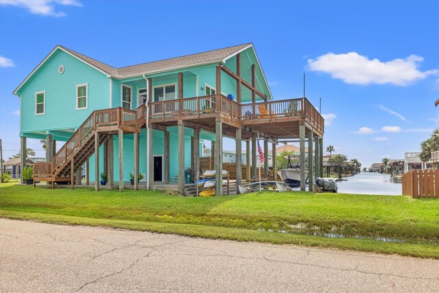 rear view of house with a yard and a deck with water view