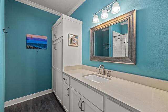 bathroom featuring crown molding, tiled shower, vanity, and wood-type flooring