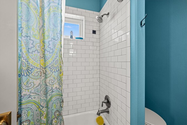 bathroom featuring toilet and shower / tub combo with curtain