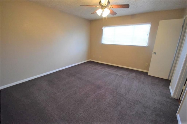 empty room featuring ceiling fan, dark carpet, and a textured ceiling