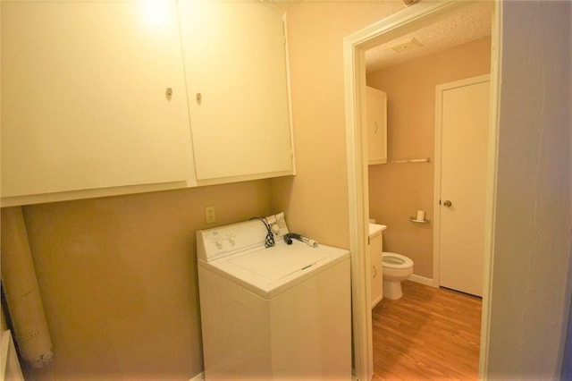 clothes washing area featuring cabinets, washer / dryer, and light hardwood / wood-style floors