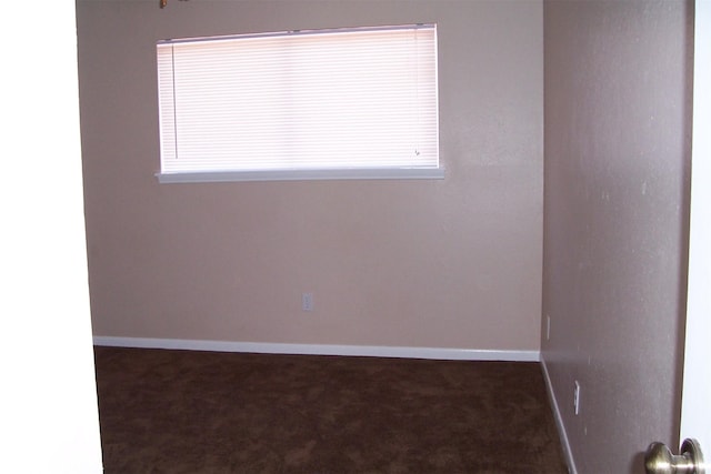 spare room featuring dark colored carpet